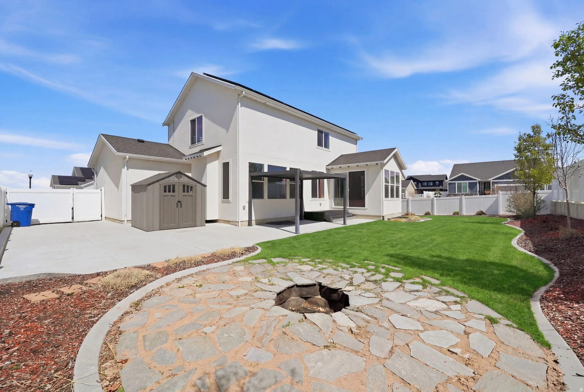 Rear view of house with a patio, a fenced backyard, an outdoor fire pit, stucco siding, and a storage shed