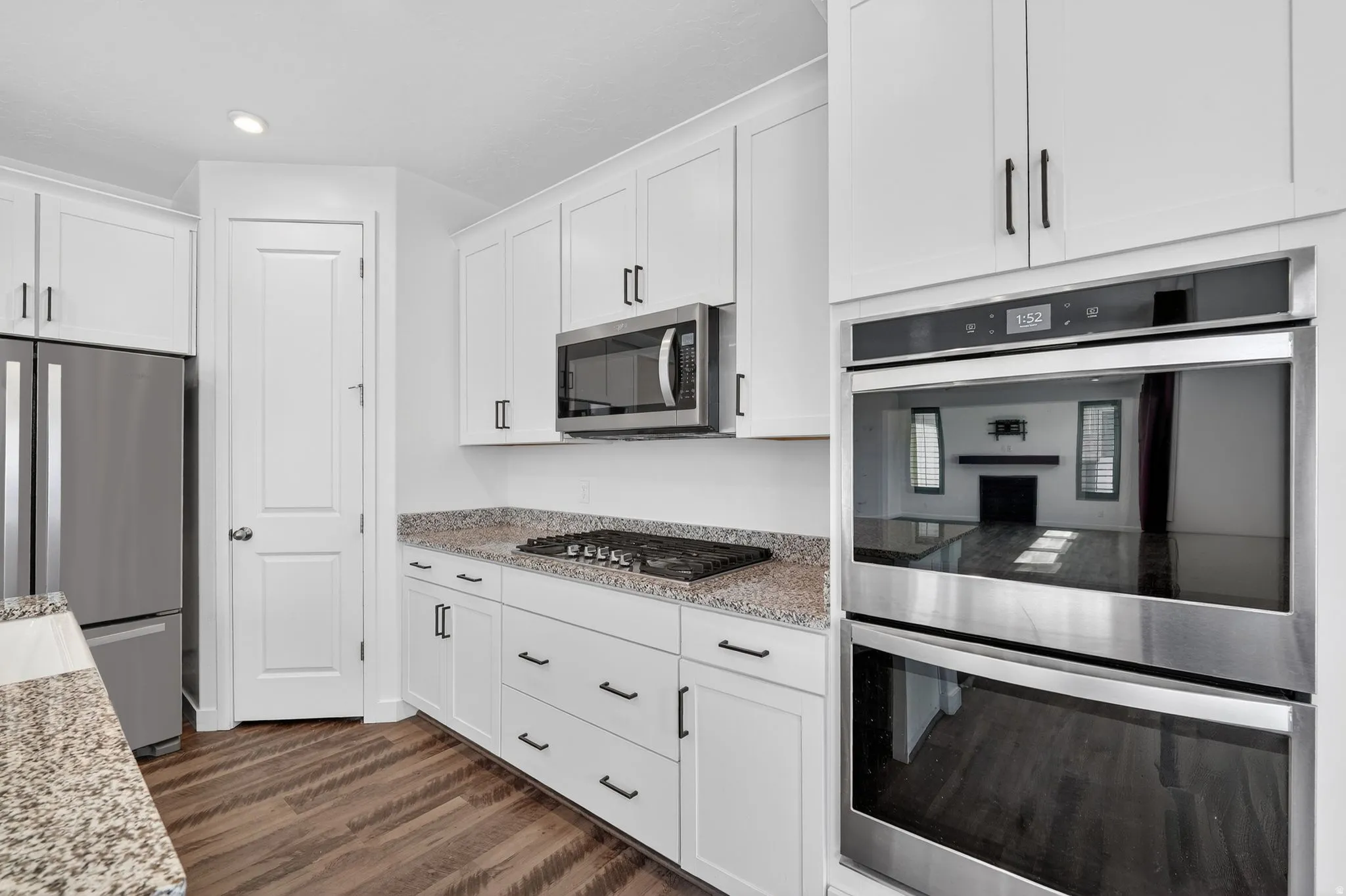 Kitchen featuring stainless steel appliances, light stone counters, white cabinets, dark wood-style floors, and recessed lighting