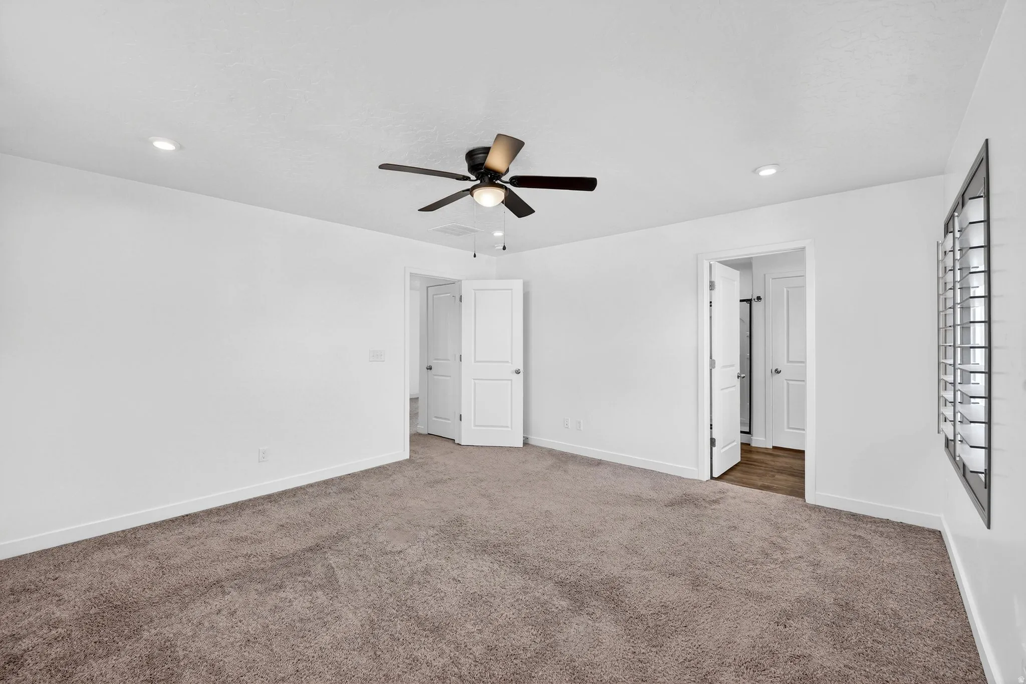 Unfurnished bedroom featuring dark colored carpet, a ceiling fan, and recessed lighting