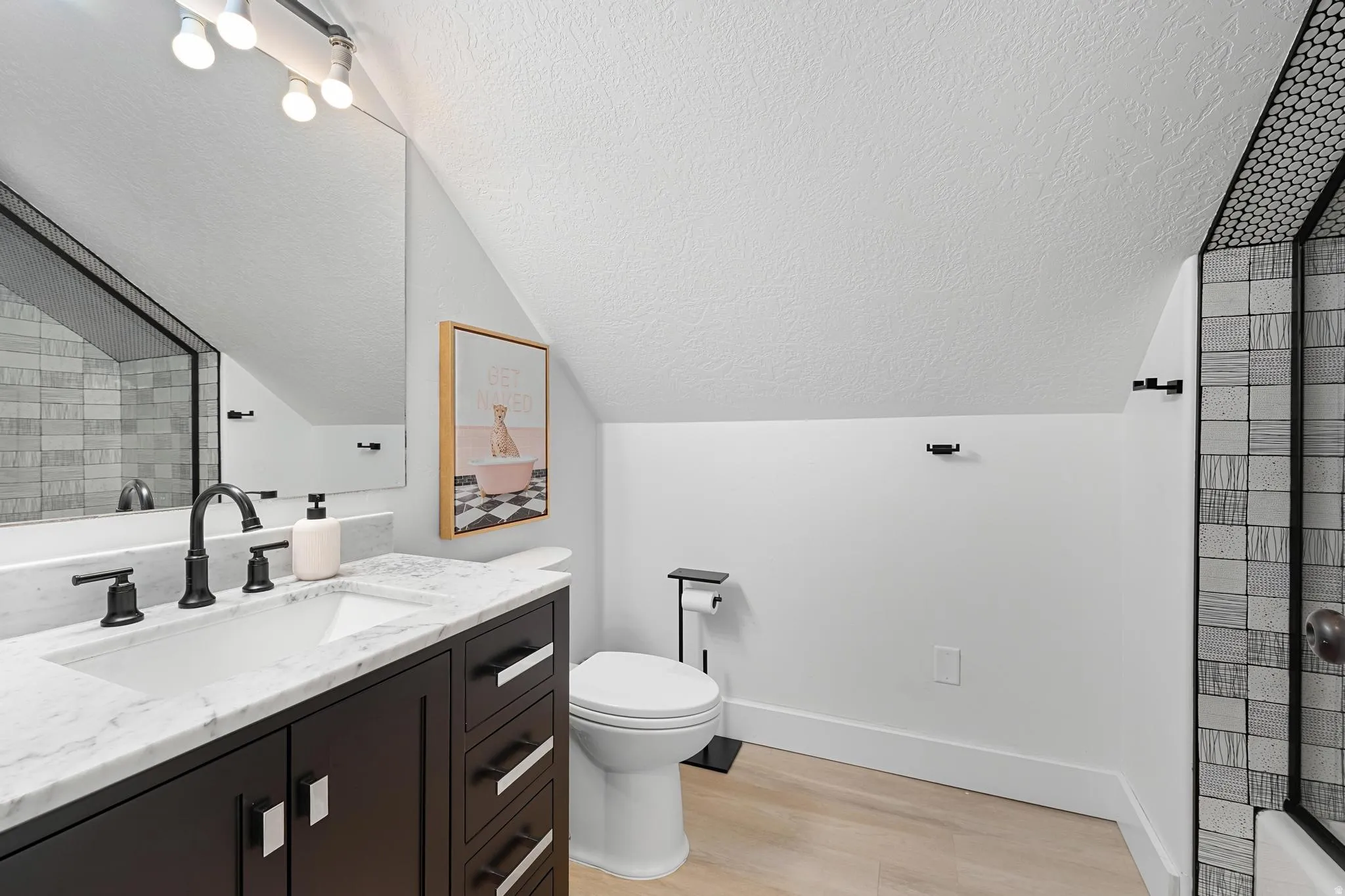Bathroom with vanity, light wood-style floors, and a tile shower