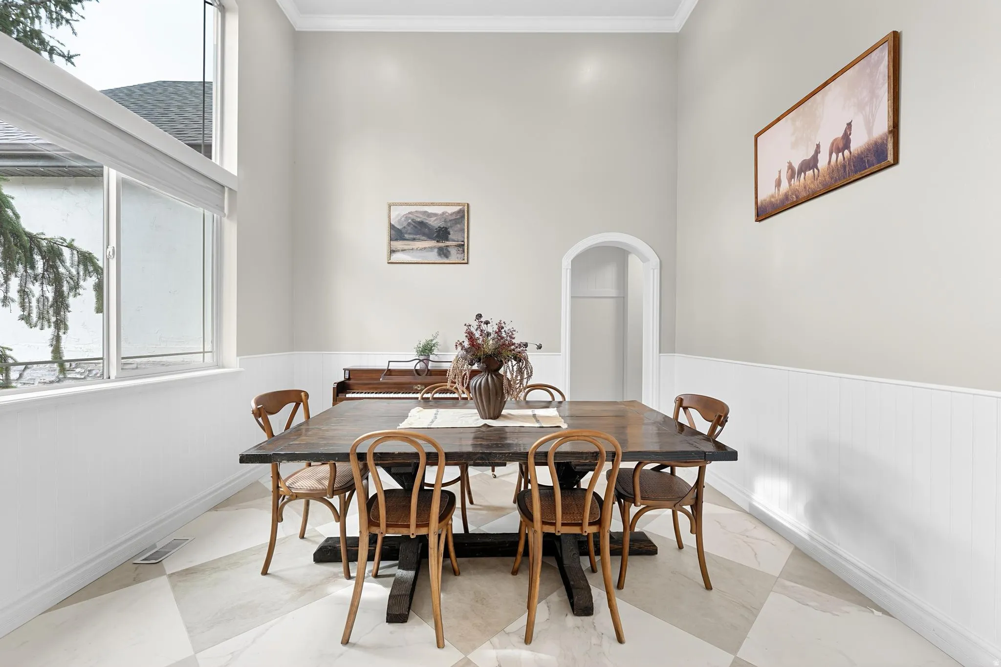 Dining space featuring arched walkways, crown molding, and a high ceiling