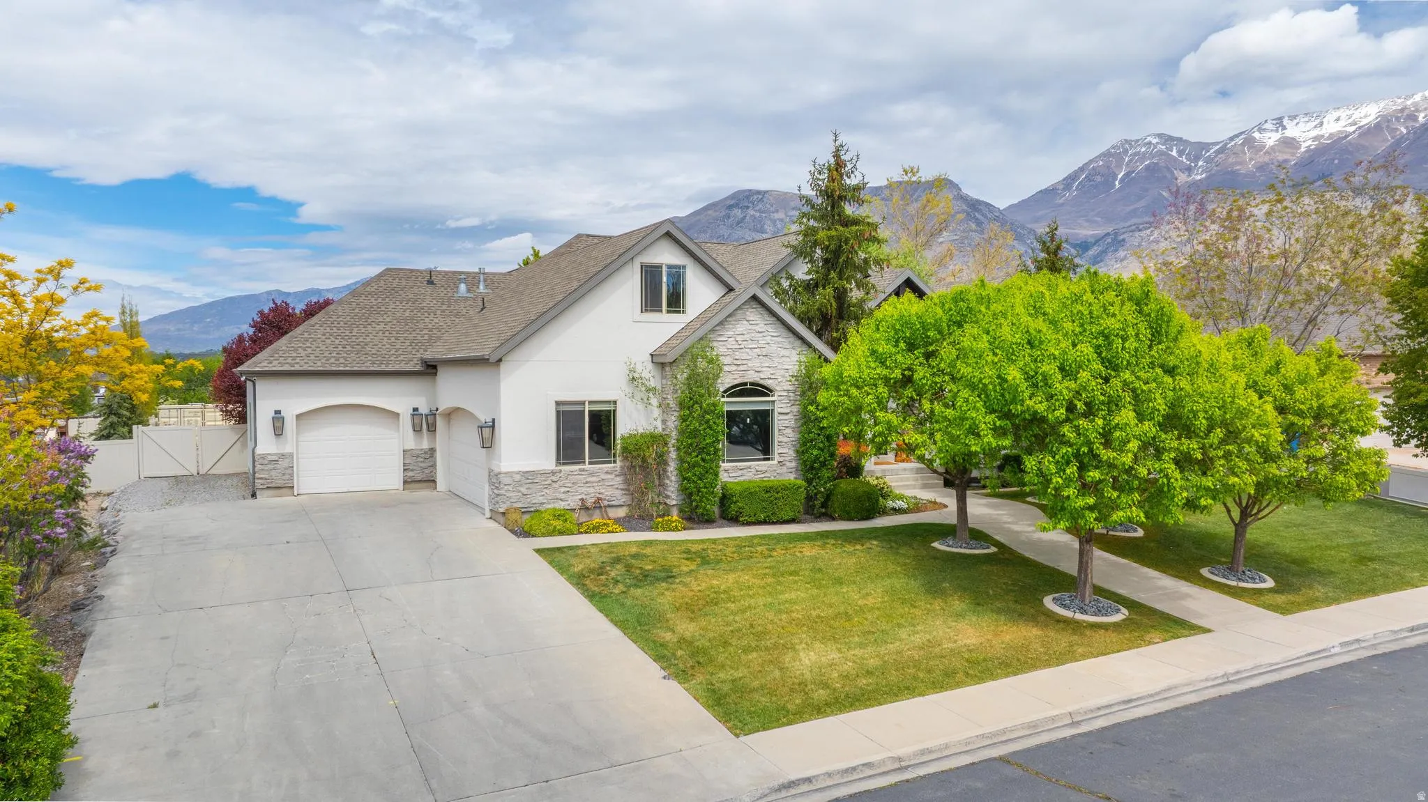 Traditional-style home featuring stone siding, a mountain view, a gate, stucco siding, and a garage