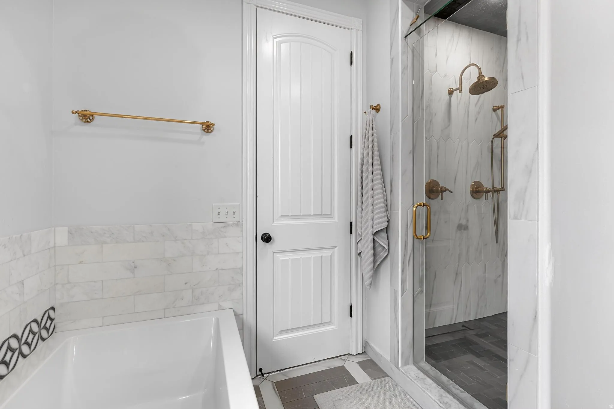 Bathroom with a marble finish shower, a garden tub, and dark tile patterned floors