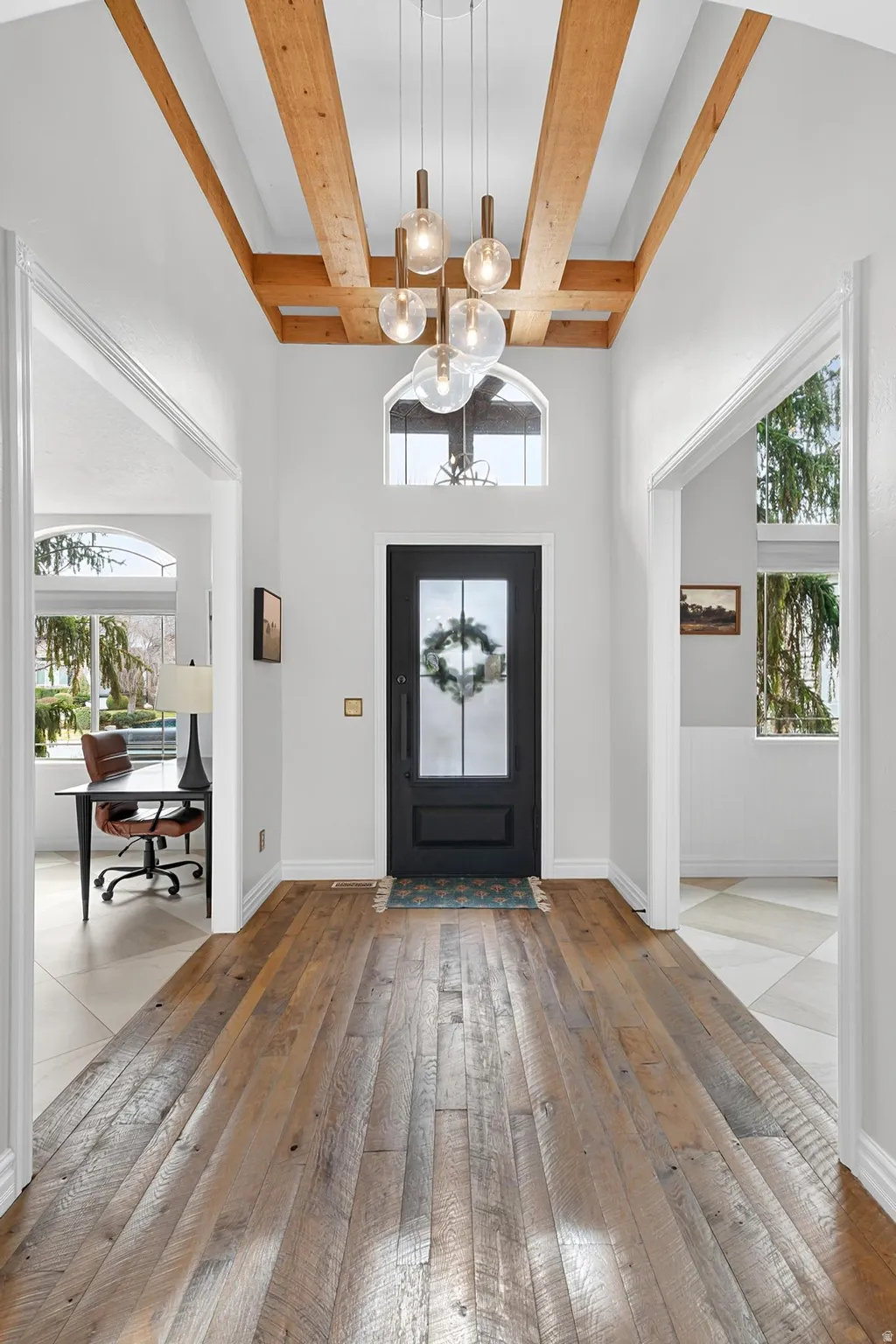Foyer entrance featuring suspended lighting, light wood-style floors, and wainscoting