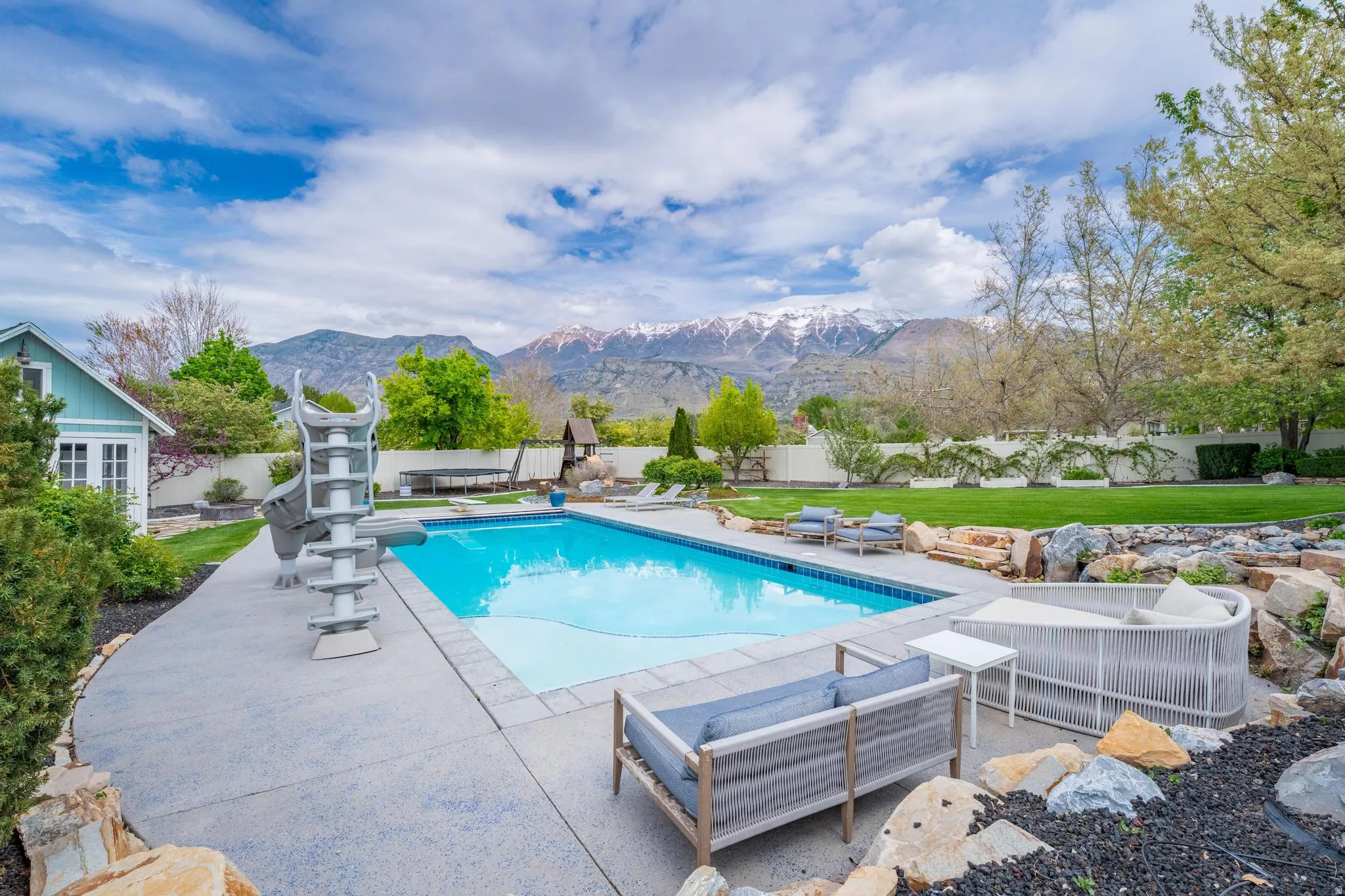 View of pool featuring patio surround, a fenced backyard, a mountain view, and a diving board