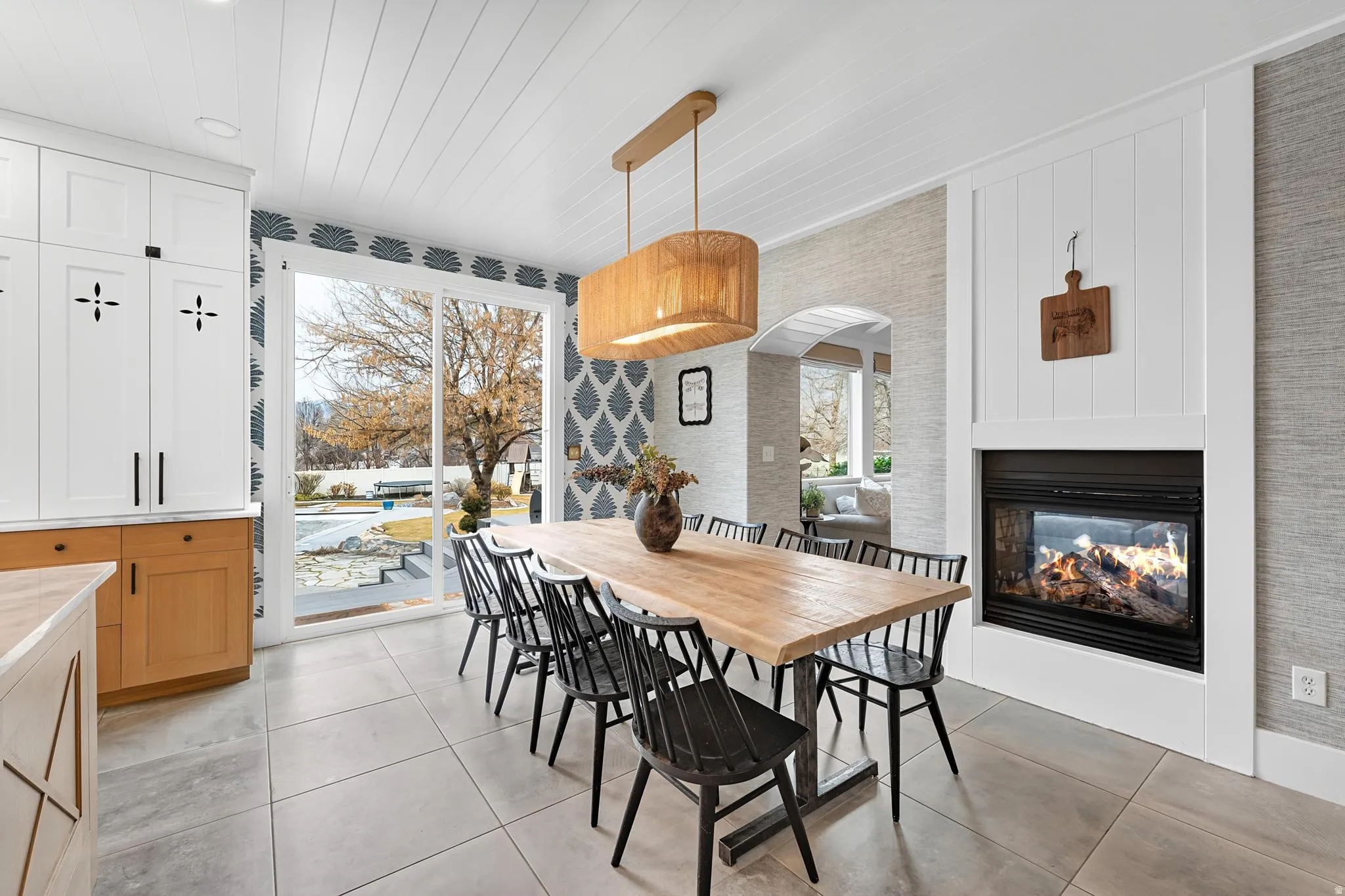 Dining room featuring a multi sided fireplace, light tile patterned floors, and wood ceiling