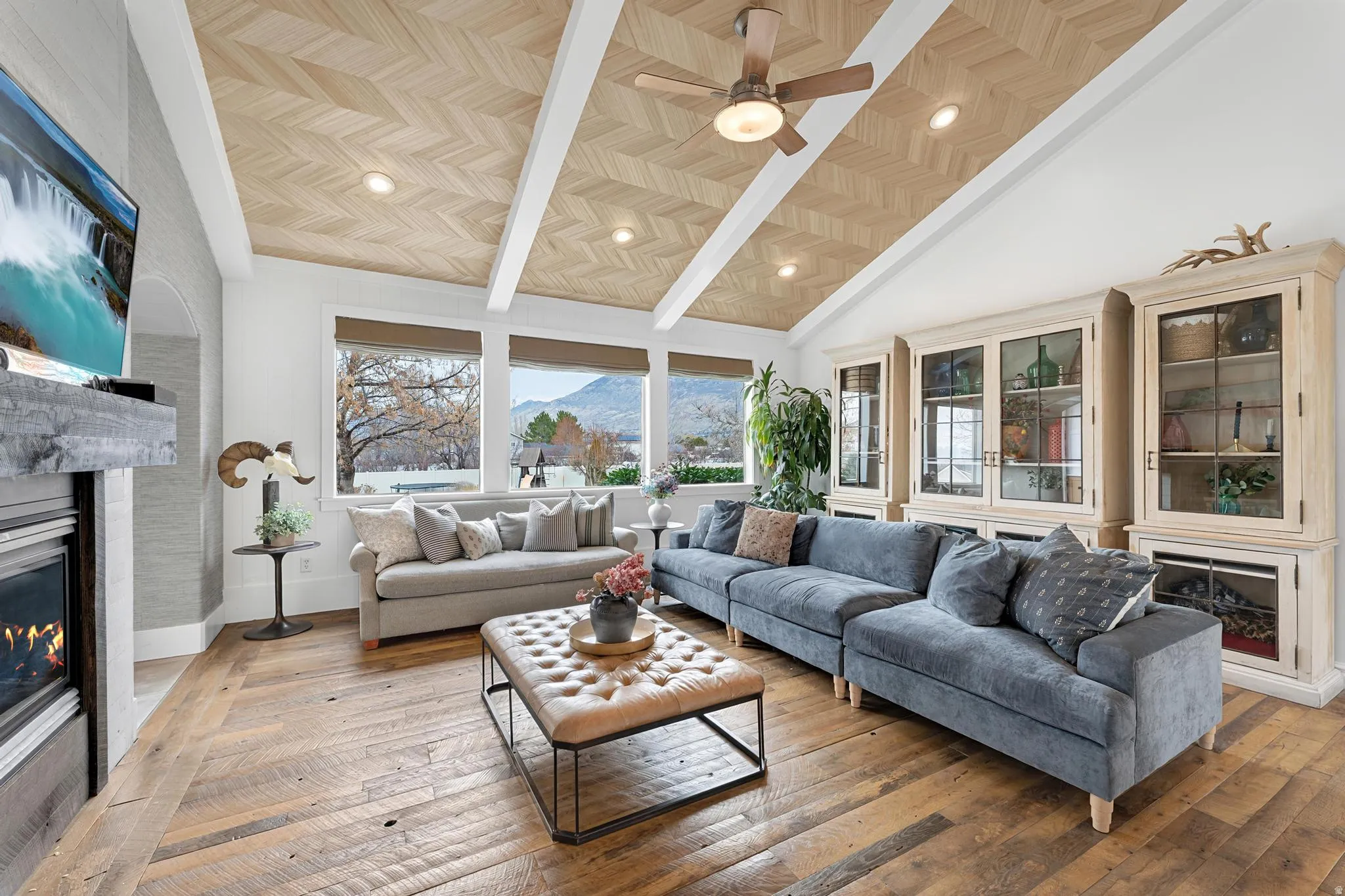 Living room featuring a glass covered fireplace, a mountain view, wood-type flooring, a ceiling fan, and lofted ceiling
