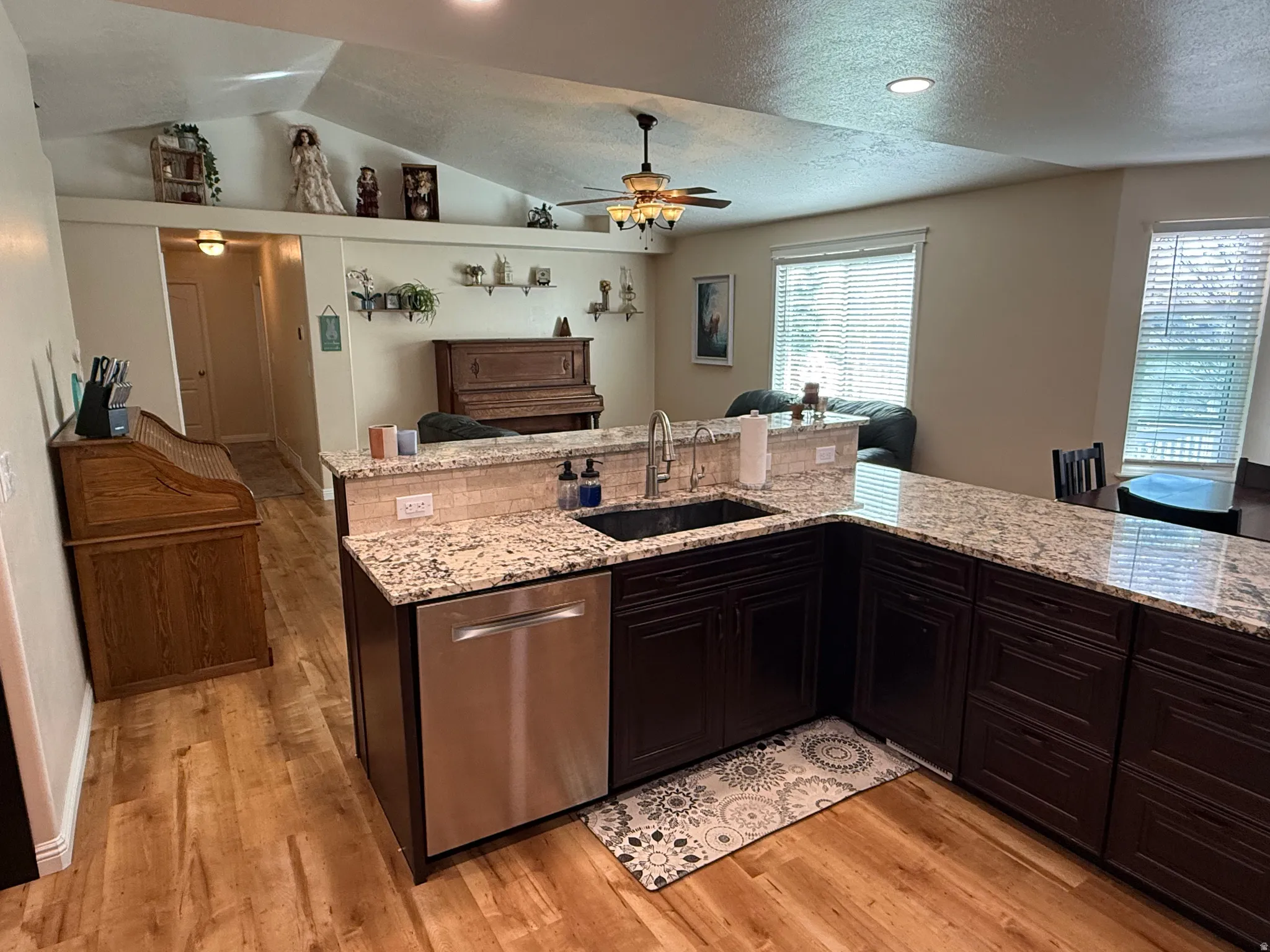 Kitchen featuring open floor plan, stainless steel dishwasher, ceiling fan, light stone counters, and recessed lighting