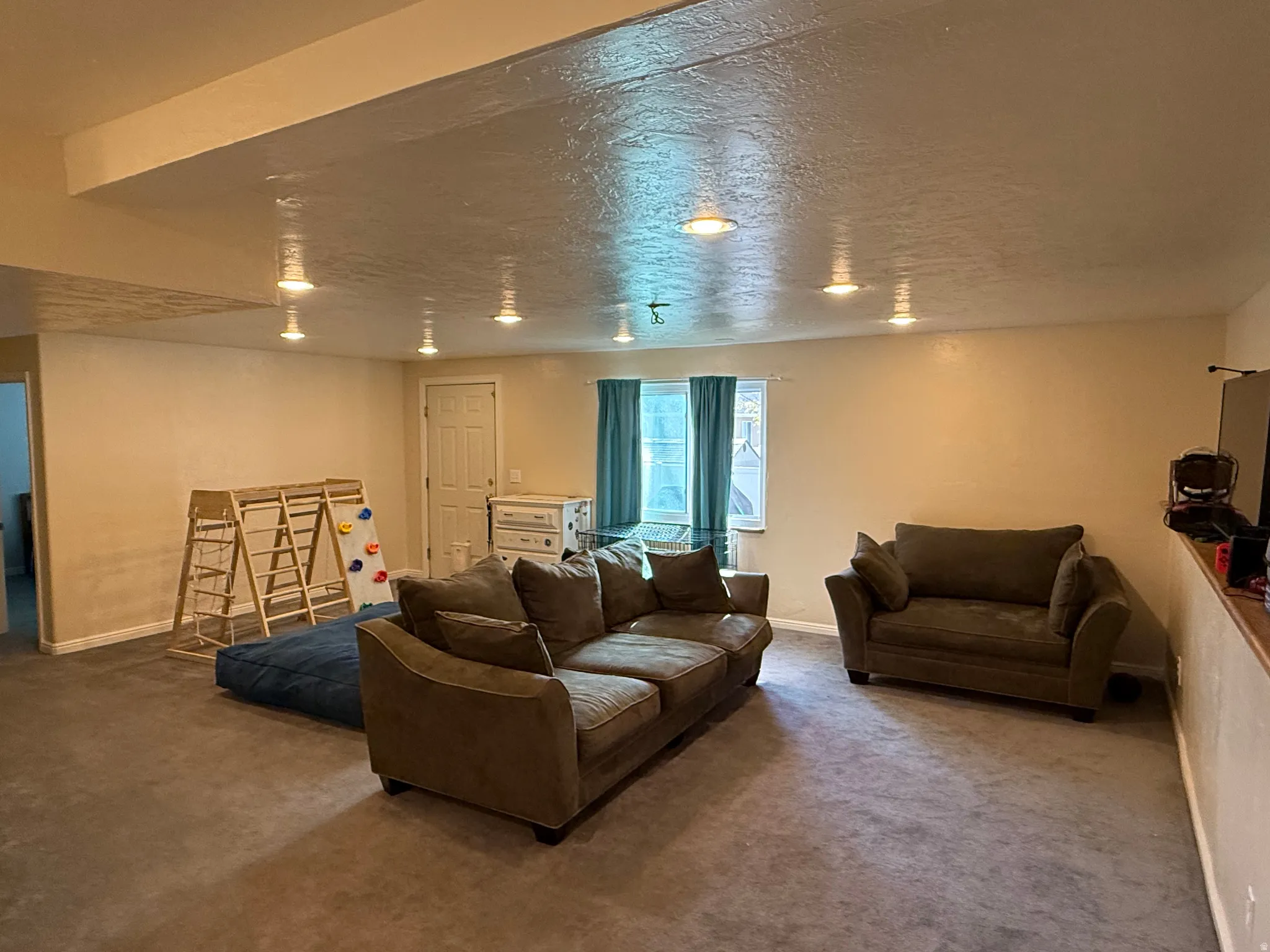 Carpeted living area featuring baseboards and a textured ceiling