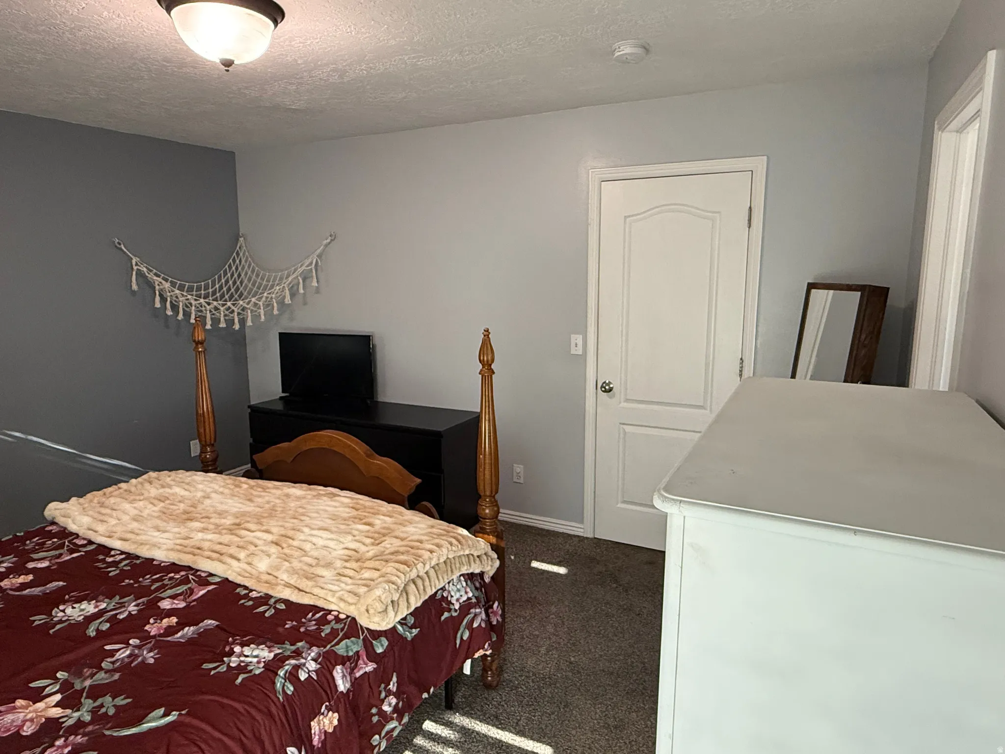 Bedroom featuring dark colored carpet and a textured ceiling