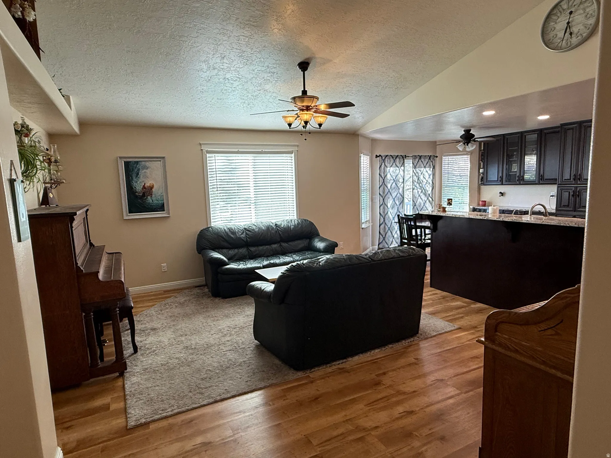 Living area featuring light wood-style flooring, plenty of natural light, and a ceiling fan
