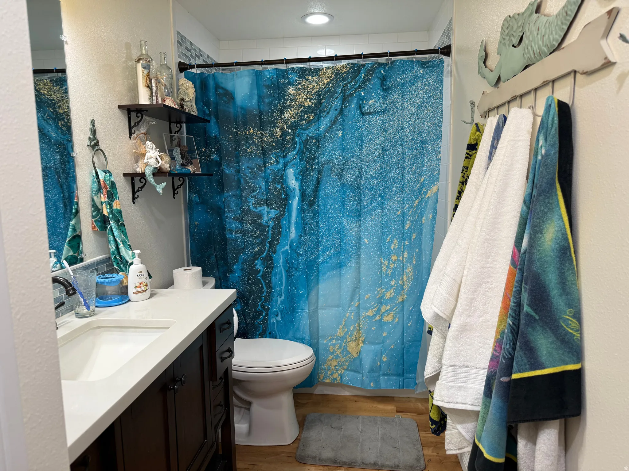 Full bath featuring vanity, light wood finished floors, a shower with shower curtain, and a textured wall