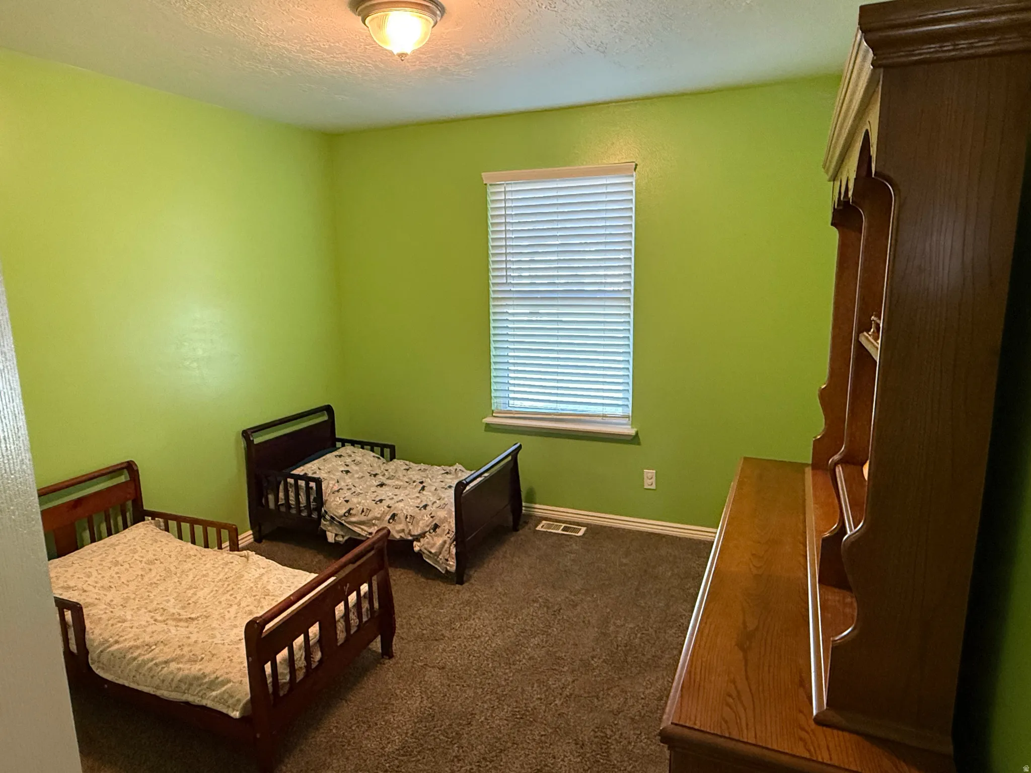 Bedroom featuring dark colored carpet and a textured ceiling