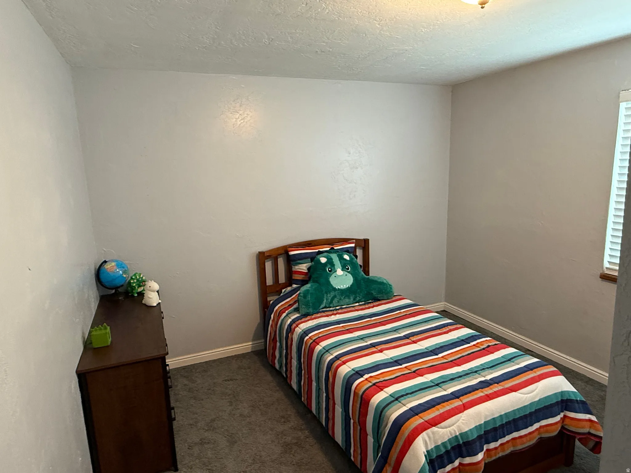 Bedroom with dark carpet and a textured ceiling