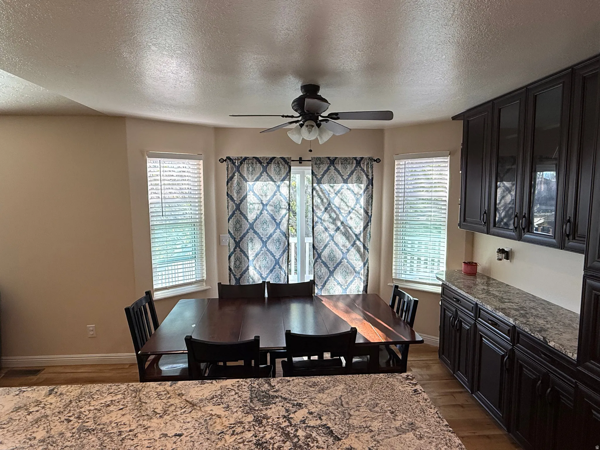 Dining area featuring a textured ceiling, dark wood-style floors, plenty of natural light, and a ceiling fan