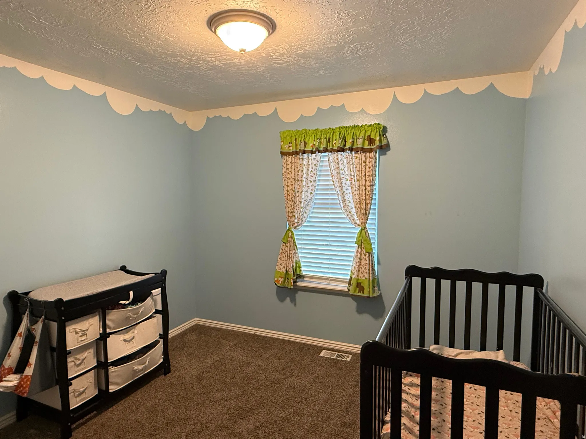 Bedroom featuring carpet floors, a textured ceiling, and a crib