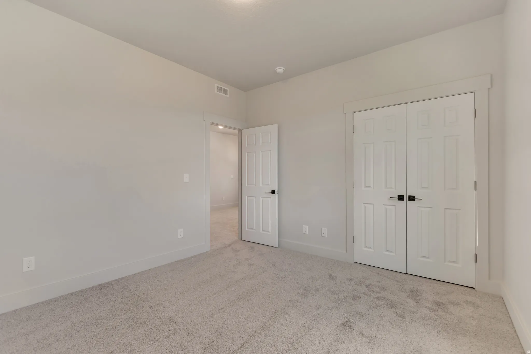 Unfurnished bedroom featuring light colored carpet and a closet