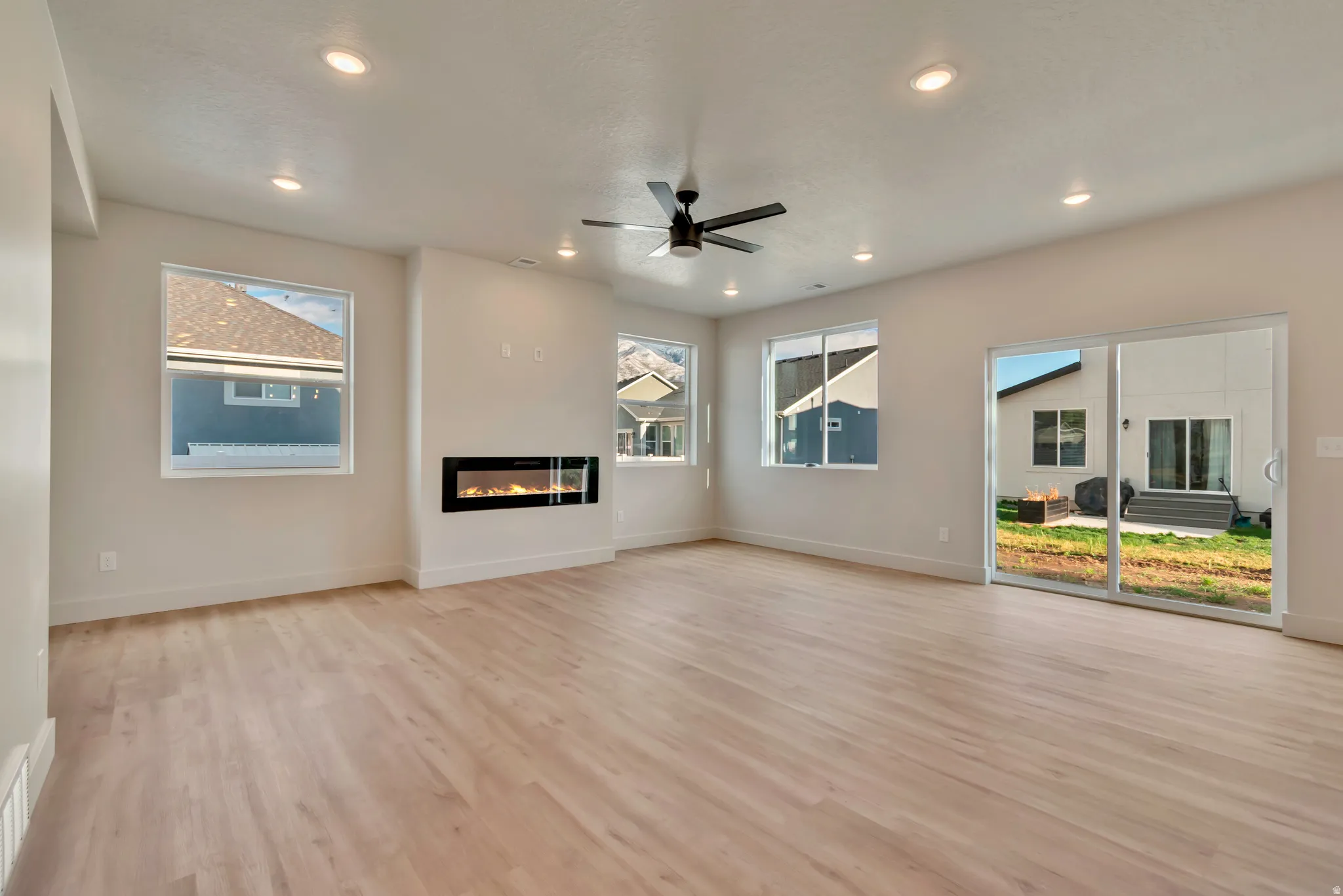 Unfurnished living room with a glass covered fireplace, light wood-type flooring, a ceiling fan, and recessed lighting