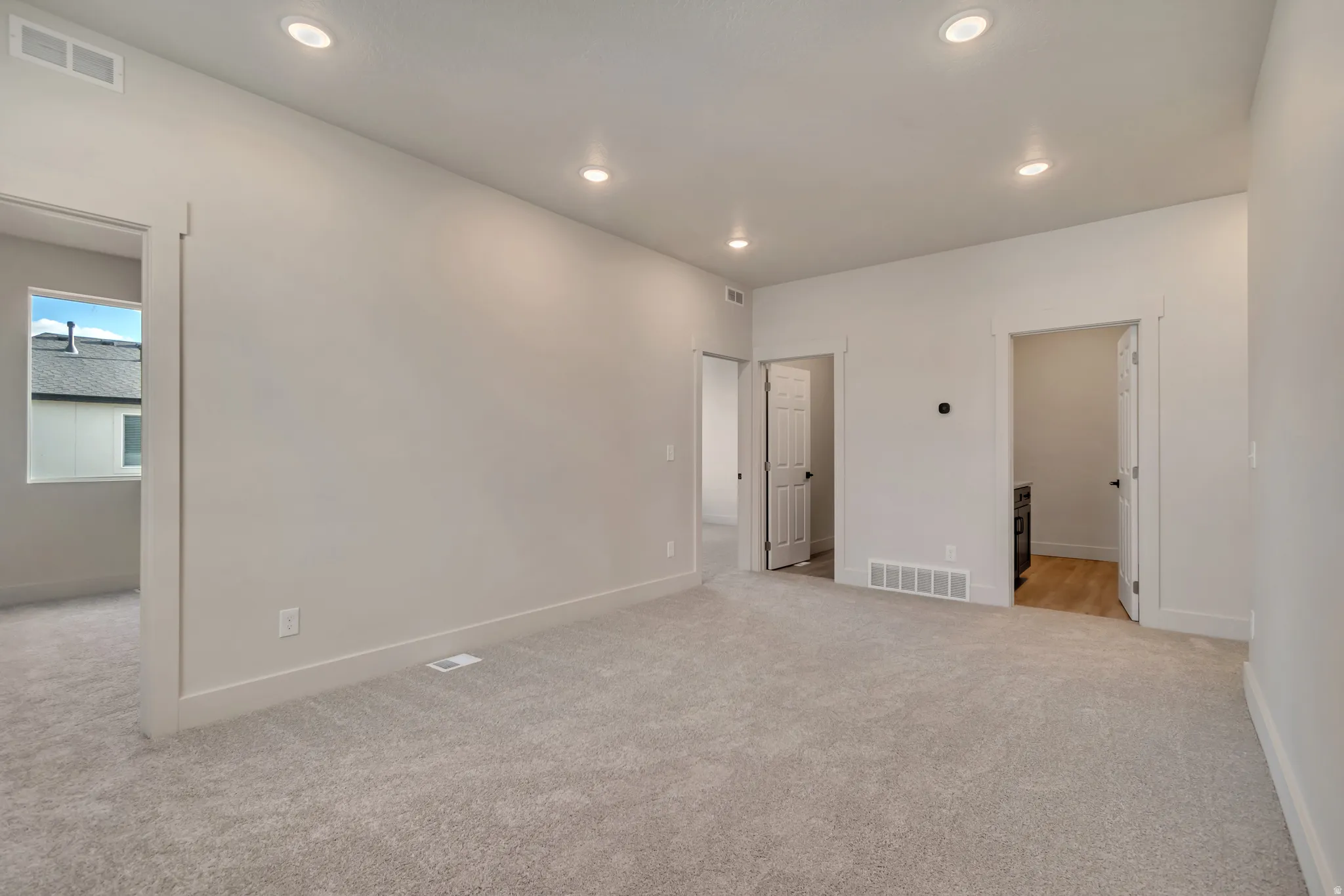 Unfurnished bedroom featuring light carpet, recessed lighting, and ensuite bathroom