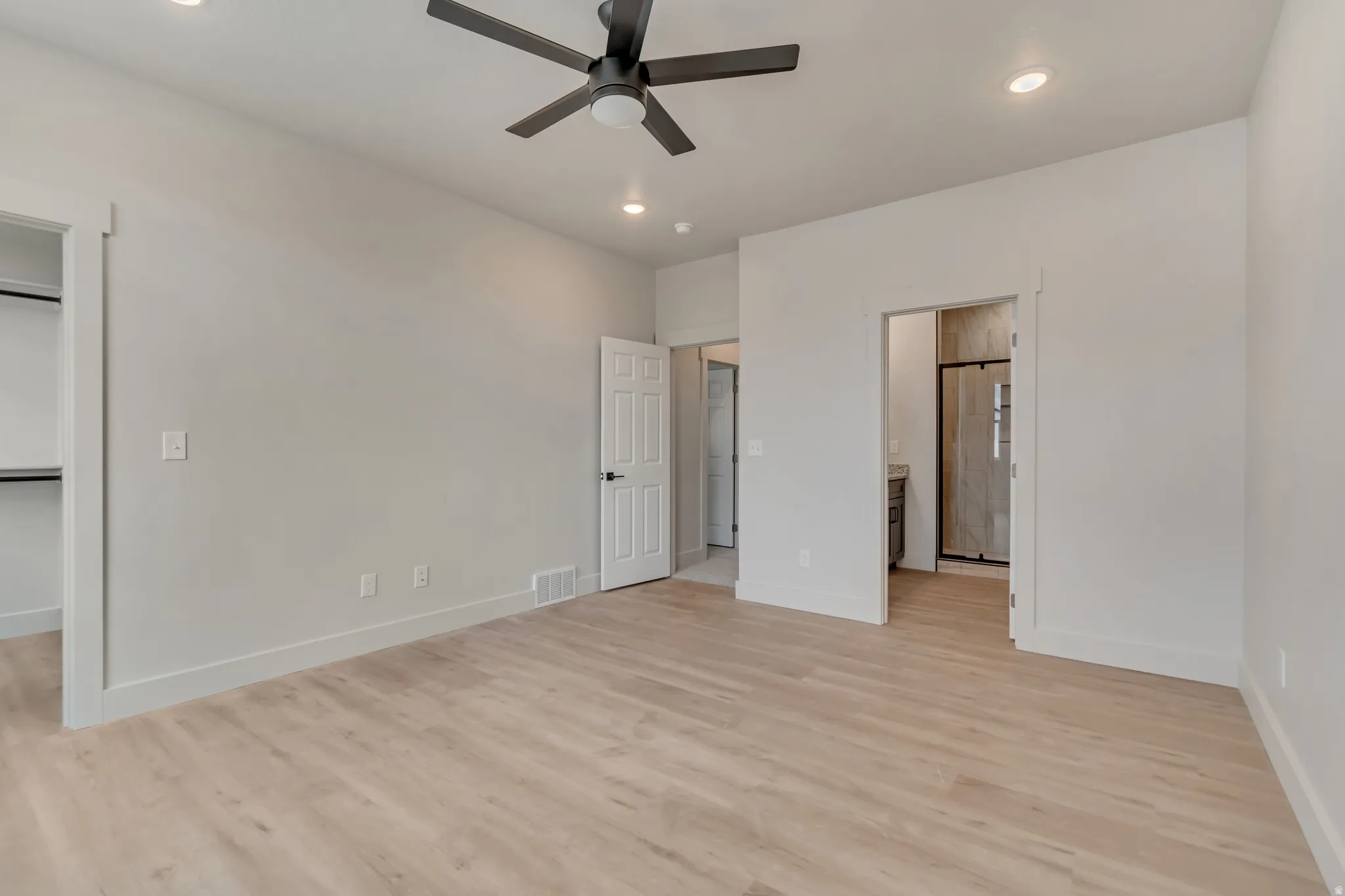 Unfurnished bedroom with recessed lighting, light wood-style floors, a walk in closet, ceiling fan, and ensuite bathroom