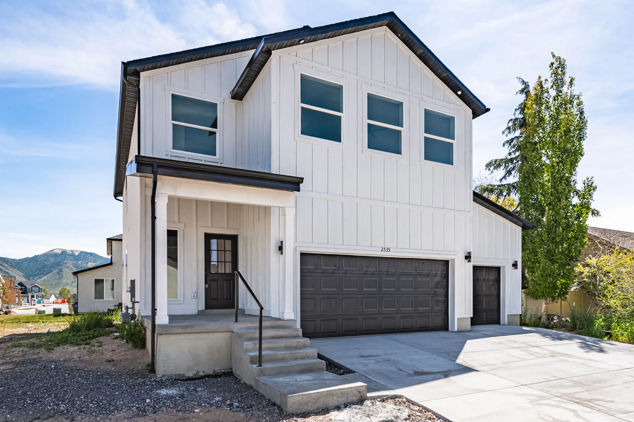 Contemporary two-story residence featuring white board and batten siding with black trim accents