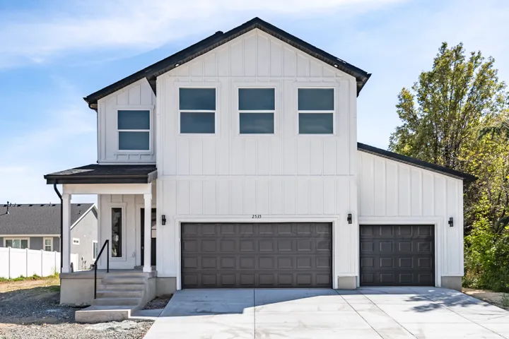 Modern farmhouse exterior featuring white vertical siding and dark trim