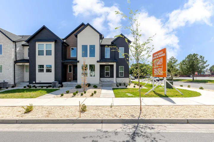 Modern two-tone exterior featuring a dark charcoal facade with cream-colored stone accents and a gabled roofline