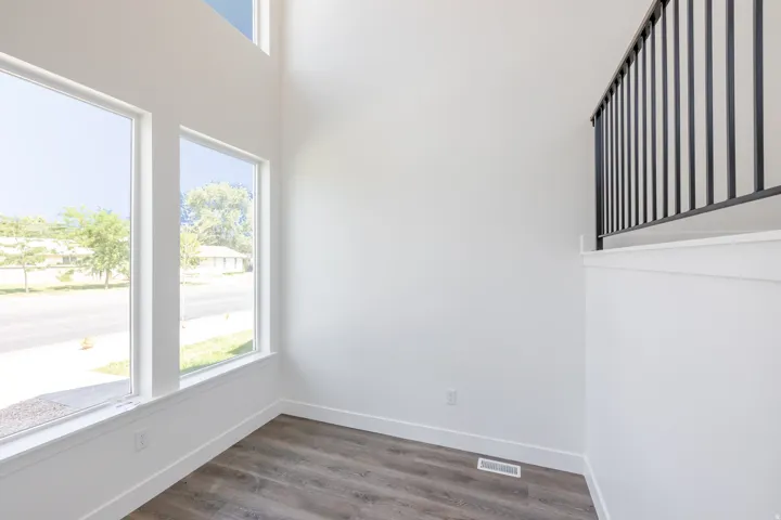 High ceilings, wood-finish flooring, white walls, black metal railing, and large windows