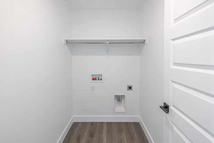 Dedicated utility closet featuring a hanging rod, water hookups, and wood-finish flooring