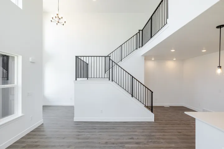 Open foyer with soaring ceilings and abundant natural light, featuring a striking metal-railing staircase with multiple landings