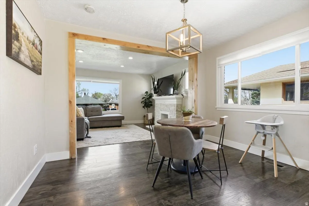 Dining area with dark wood-type flooring, a fireplace, and a chandelier