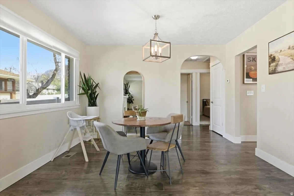 Dining space featuring dark wood finished floors, hanging lights, and arched walkways