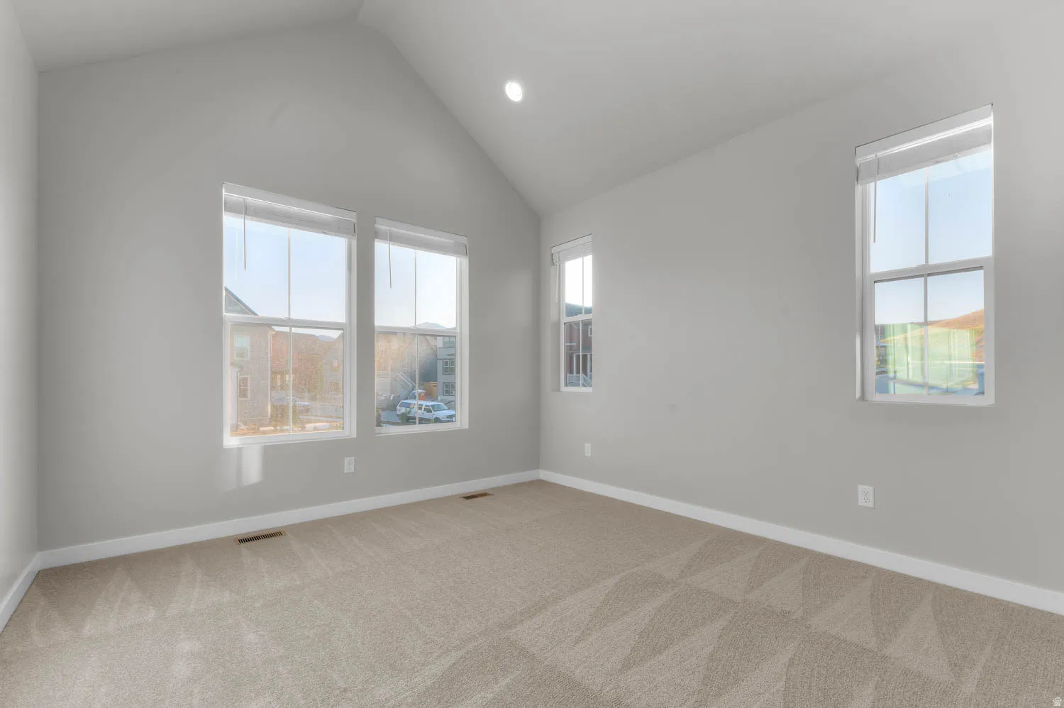 Spare room featuring light carpet, recessed lighting, and lofted ceiling
