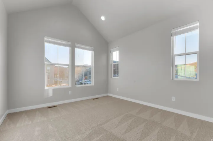 Spare room featuring light carpet, recessed lighting, and lofted ceiling