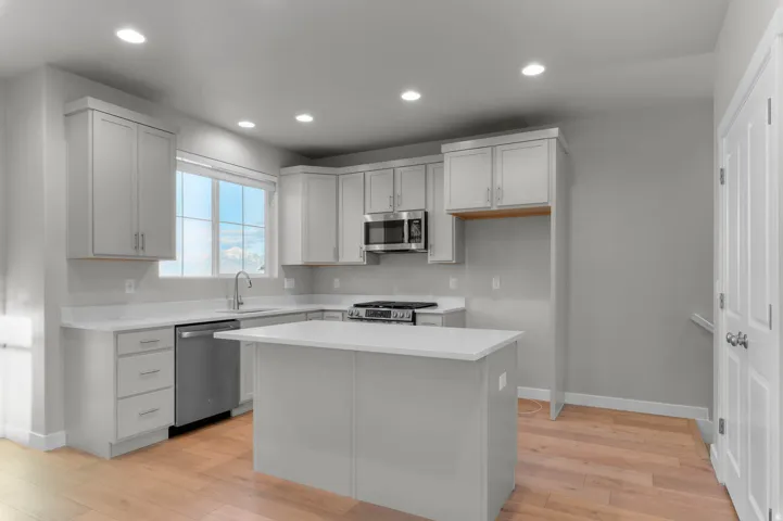 Kitchen with stainless steel appliances, light wood-style floors, a kitchen island, and recessed lighting