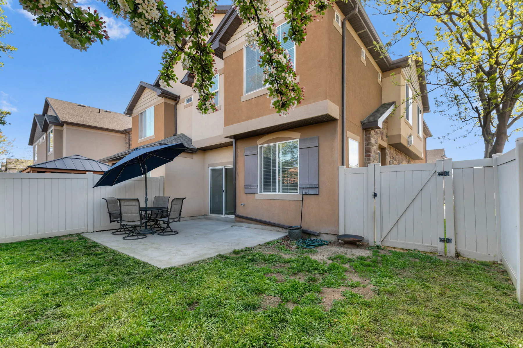 Rear view of property with a gate, a fenced backyard, stucco siding, and a patio area