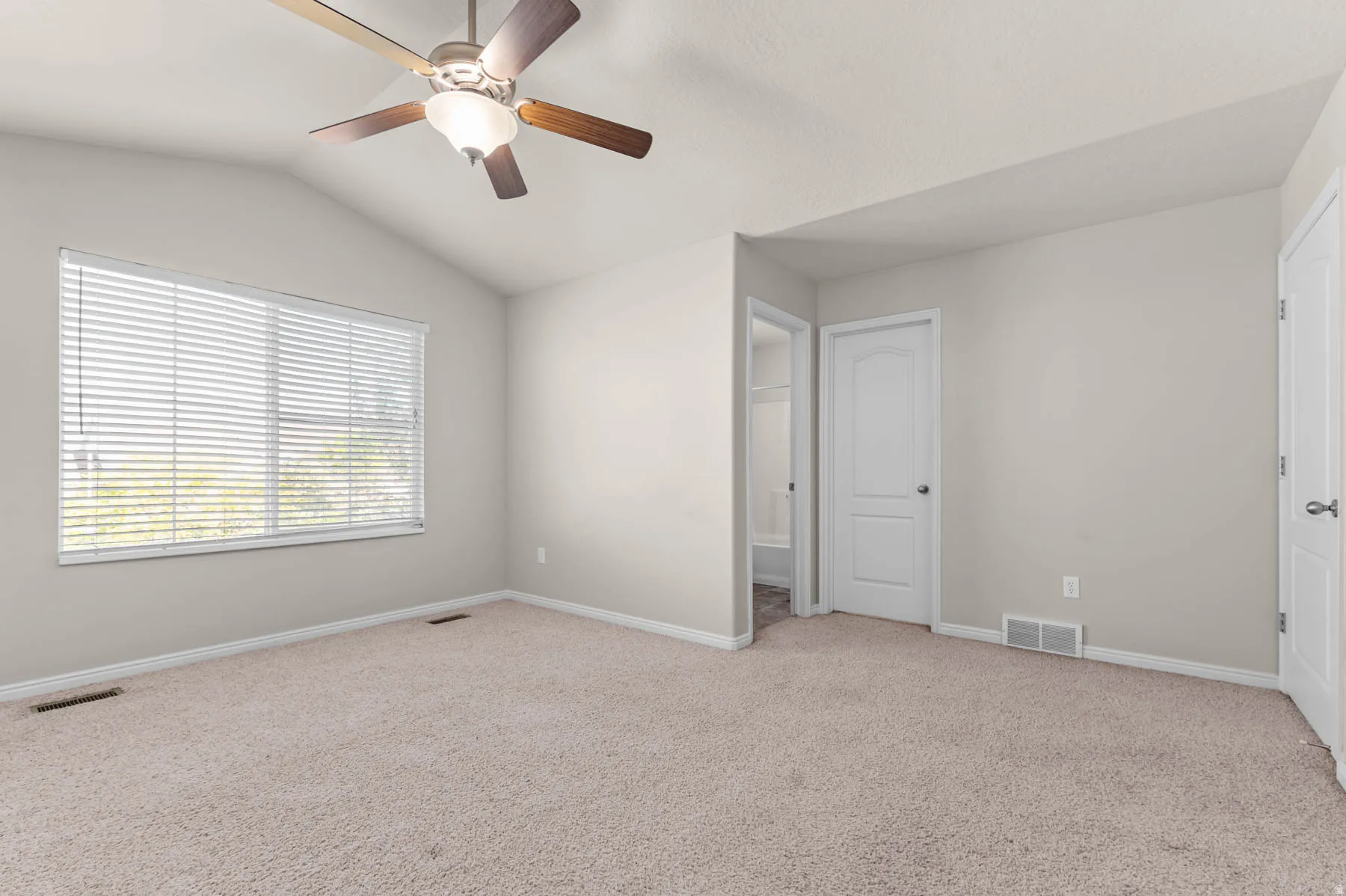 Unfurnished bedroom with carpet flooring, lofted ceiling, a ceiling fan, and ensuite bathroom