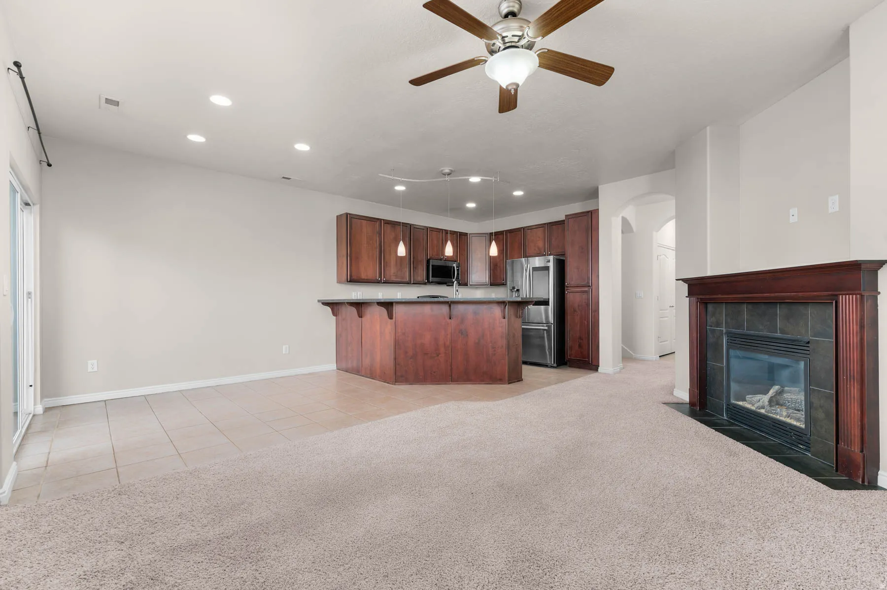 Kitchen featuring open floor plan, a breakfast bar, arched walkways, and a tiled fireplace
