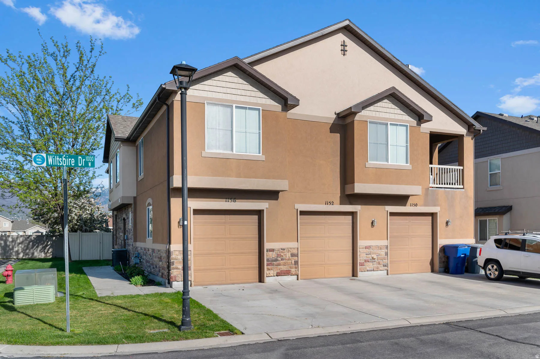 View of front of property featuring an attached garage, stone siding, stucco siding, and driveway