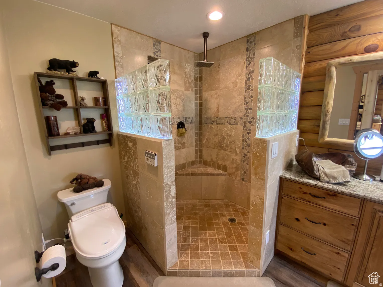 Bathroom featuring vanity, a walk in shower, wood finished floors, and log walls