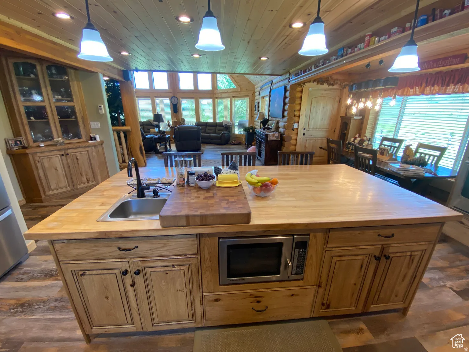 Kitchen with wooden counters, decorative light fixtures, open floor plan, stainless steel appliances, and wooden ceiling