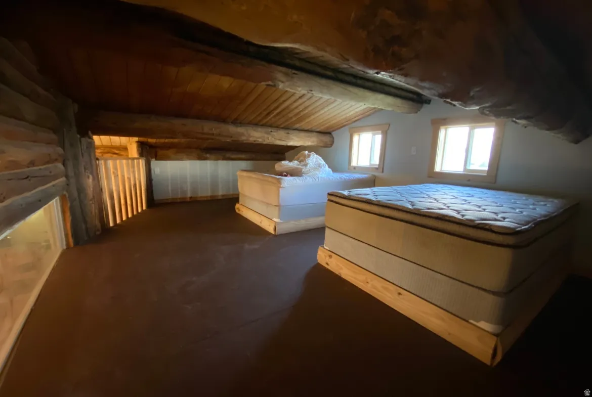 Bedroom featuring a vaulted wooden ceiling and log walls