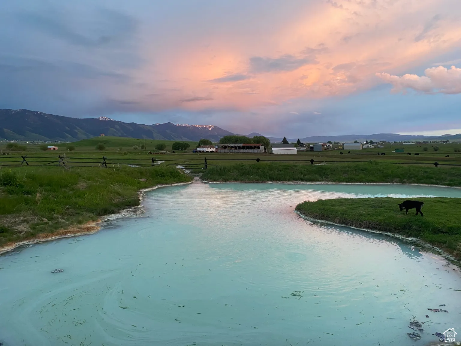 Pool at dusk with a rural view, a lawn, and a water and mountain view