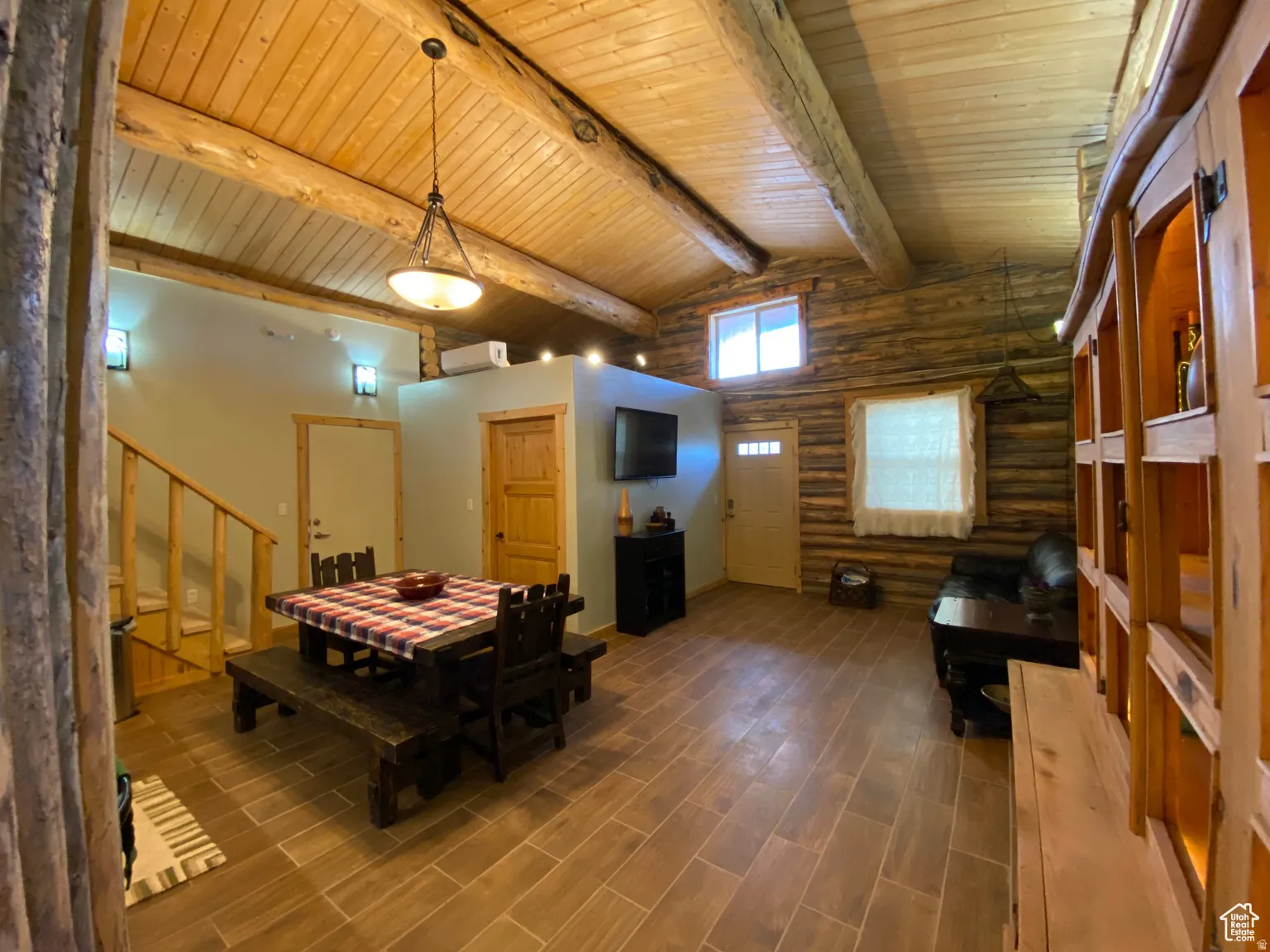 Dining space with log walls, wood tiled floors, and a wooden ceiling with exposed beams