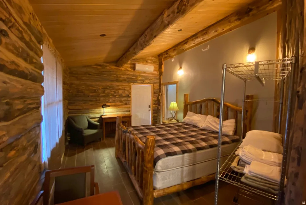 Bedroom with hardwood / wood-style floors, vaulted ceiling with beams, and wood ceiling