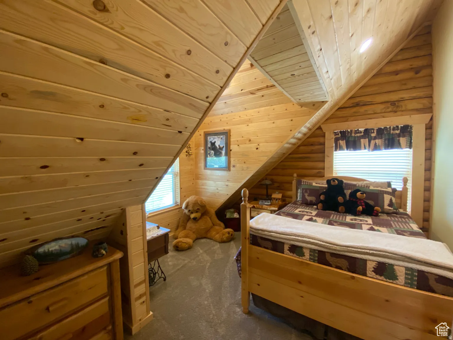 Bedroom with a vaulted wooden ceiling, dark colored carpet, and log walls