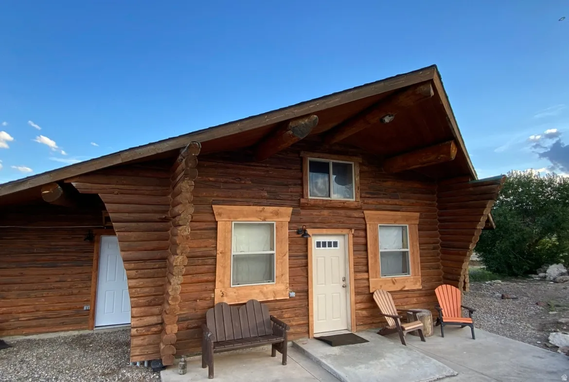 Back of house with log exterior and a patio