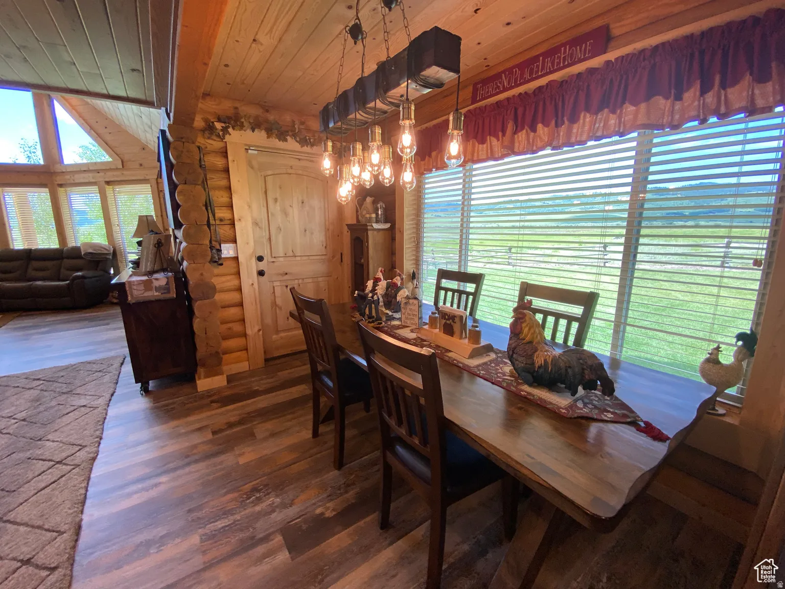Dining space featuring log walls, dark wood finished floors, wood ceiling, and a chandelier