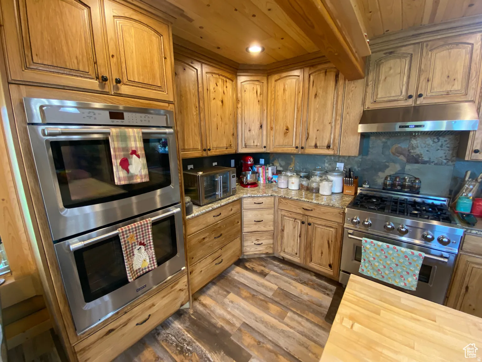 Kitchen featuring stainless steel appliances, wood counters, a wood ceiling with exposed beams, backsplash, and light wood-style flooring