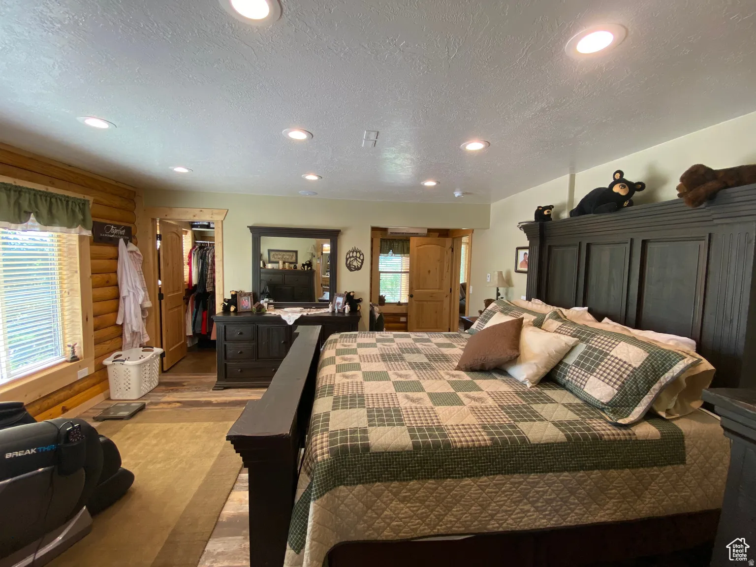 Bedroom featuring rustic walls, a textured ceiling, recessed lighting, a spacious closet, and wood finished floors